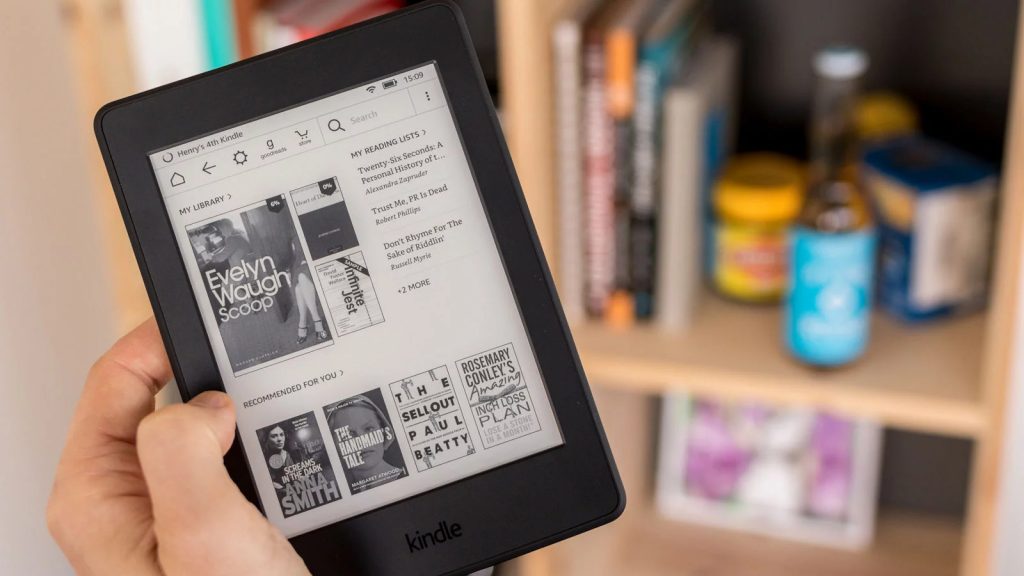 Kindle de Amazon en la mano de una mujer con revistas abiertas para la lectura